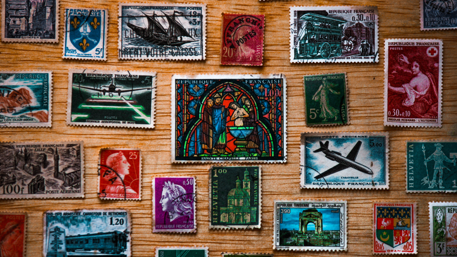 "Direct Mail Postcards Key Stats & Essential Tips - A collection of vintage postage stamps featuring vibrant designs, displayed on a wooden background